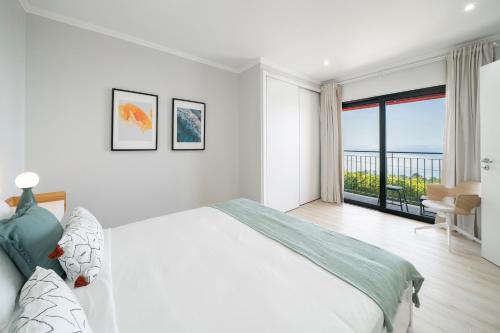 Biała sypialnia z dużym łóżkiem i balkonem w obiekcie Vilas Felicidade Rocha by An Island Apart w mieście Ponta do Pargo