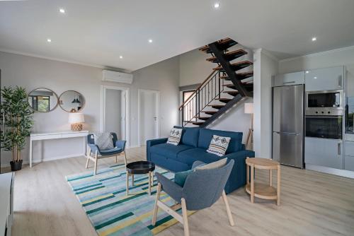 a living room with a blue couch and a staircase at Vilas Felicidade Rocha by An Island Apart in Ponta do Pargo