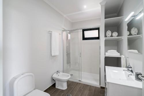 a white bathroom with a toilet and a shower at Vilas Felicidade Rocha by An Island Apart in Ponta do Pargo