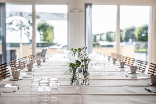 a long table with glasses and flowers in vases at Molskroen Strandhus in Ebeltoft