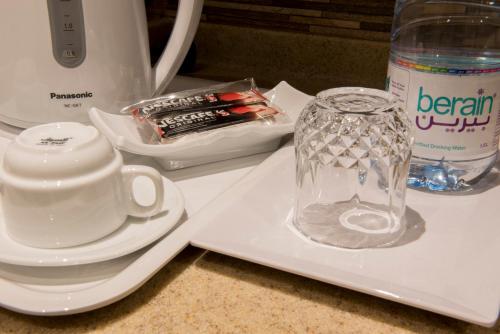 a glass vase sitting on a plate next to a blender at نورمينا الشرق للشقق المخدومة in Dammam