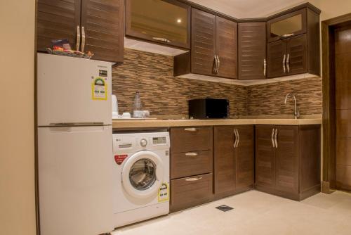 a kitchen with a white refrigerator and a washing machine at نورمينا الشرق للشقق المخدومة in Dammam