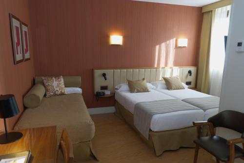 a hotel room with two beds and a couch at Hospedium Hotel Los Condes in Madrid