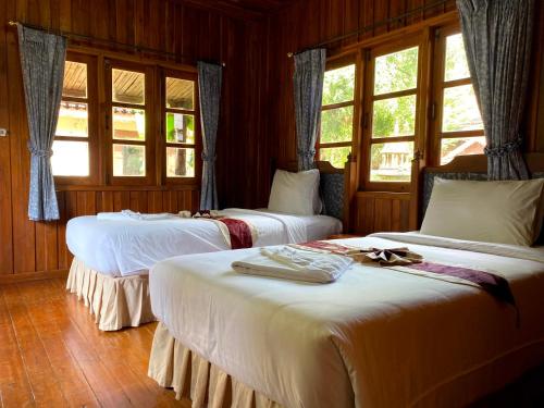 two beds in a room with windows at Yuwadee Resort in Chalong