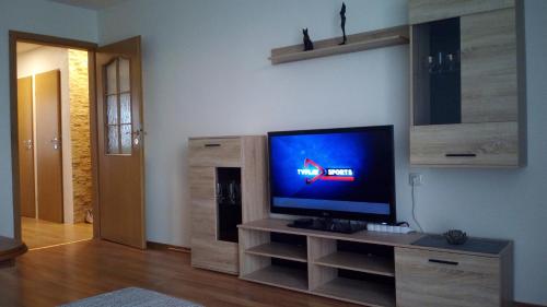 sala de estar con TV de pantalla plana en un centro de entretenimiento en Bright apartment on top en Panevėžys