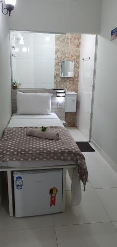 a small room with a bed and a small bathroom at Pertinho do Aeroporto Hospedagem Particular in Várzea Grande