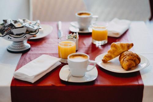 a table with cups of coffee and pastries and orange juice at Hotel La Valle dell'Aquila in LʼAquila