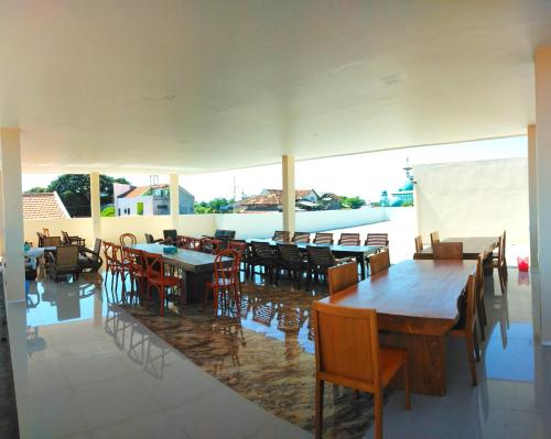 un restaurant avec des tables et des chaises en bois et une piscine dans l'établissement Bluefire Homestay Syariah, à Banyuwangi