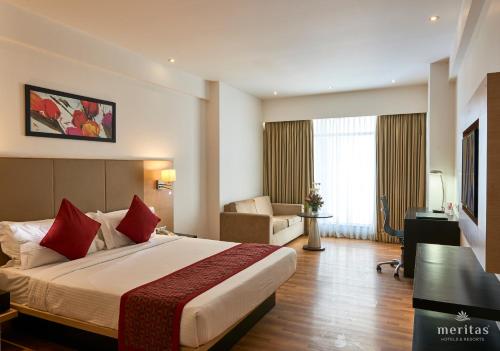 ロナバラにあるMeritas Picaddle Resort Lonavalaの大きなベッドと椅子が備わるホテルルームです。