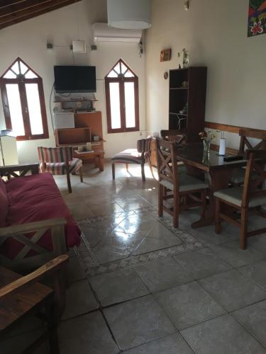 sala de estar con mesa, sillas y ventanas en Chalet en Villa Gesell en Villa Gesell