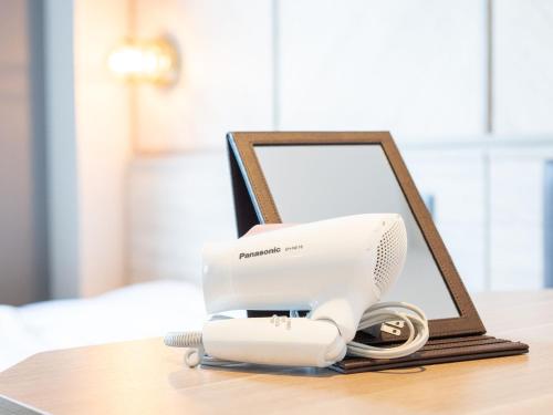 a hair dryer on a table next to a mirror at SUPERHOTEL Matsumoto Oshiroguchi in Matsumoto