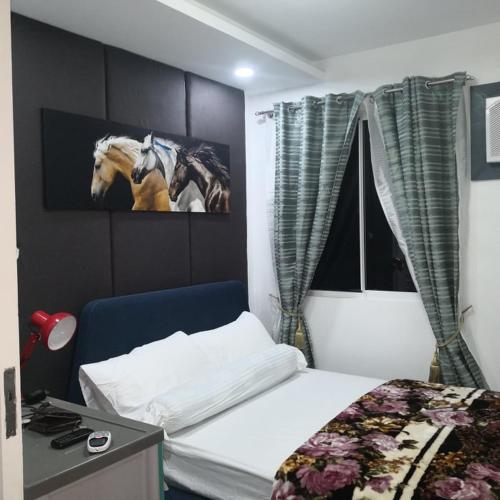 a bedroom with a bed and a picture of a horse on the wall at 426 Anabelle Residence at Marina Spatial Condominium in Dumaguete