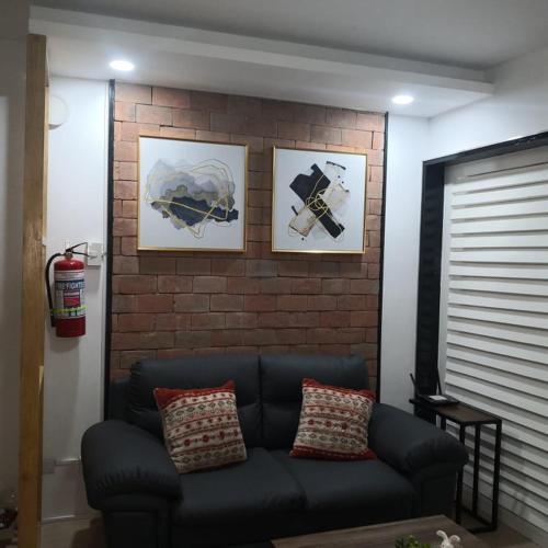 a couch in a living room with pictures on a brick wall at 426 Anabelle Residence at Marina Spatial Condominium in Dumaguete