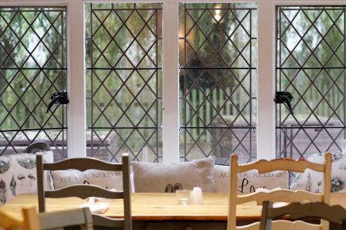 a table and chairs in a room with windows at The Priest House On The River in Castle Donington