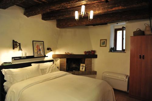 a bedroom with a white bed and a fireplace at Casa Messi in Pitigliano