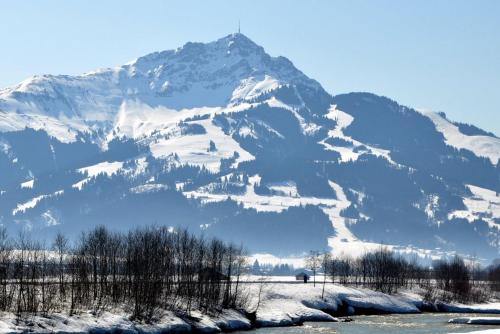 a snow covered mountain in front of a river at Haus Treffer in Kirchdorf in Tirol