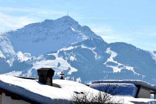 a snow covered mountain with a cross on top of a house at Haus Treffer in Kirchdorf in Tirol