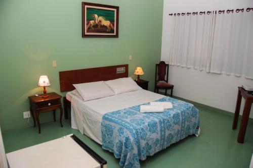 1 dormitorio con 1 cama con 2 toallas en Hotel Salvador, en Poços de Caldas
