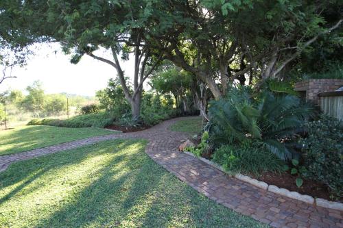 a brick path in a yard with trees and grass at Modjadji Estate Lodge & Spa in Grietjie Nature Reserve
