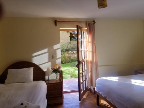 a bedroom with a bed and a door to a yard at Apu Lodge in Ollantaytambo