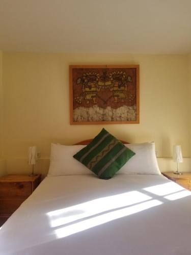 a bedroom with a white bed with a picture on the wall at Apu Lodge in Ollantaytambo