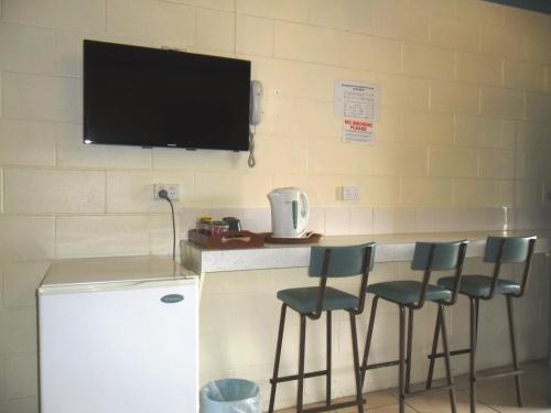 eine Küche mit einer Theke mit Stühlen und einem TV an der Wand in der Unterkunft Nanango Antler Motel in Nanango
