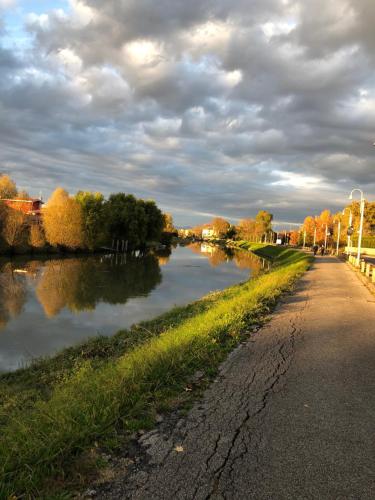 a river next to a road with trees in the background at Barchessa Rossetti in Concordia Sagittaria