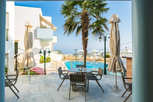 a patio with a table and chairs and a palm tree at Radamanthy's Hotel Apartments in Sfakaki