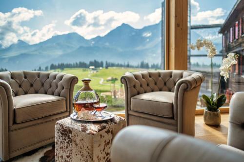 a room with two chairs and a glass of wine on a table at Golf- & Sporthotel Hof Maran in Arosa