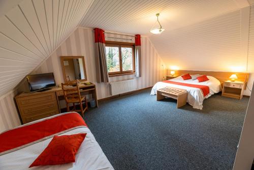 a bedroom with two beds and a desk and a television at Logis - Hotel Restaurant La Sapinière in Wisques