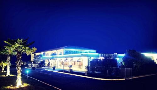 a building with a palm tree in front of it at night at Citotel Hôtel Le Capricorne in Marmande