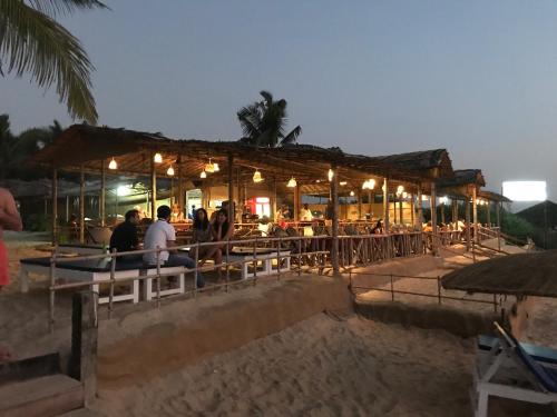 a restaurant on the beach at night with people at Blue Corner Beach Huts & Restaurant in Benaulim