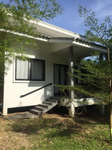 a small white house with stairs in a yard at DG House in Thongsala