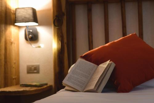 a book sitting on top of a bed with a pillow at Serendipity Hotel in Sauze dʼOulx