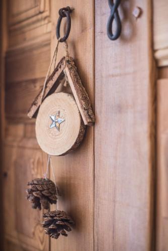 a clock hanging on a wooden wall with pine cones at Serendipity Hotel in Sauze dʼOulx