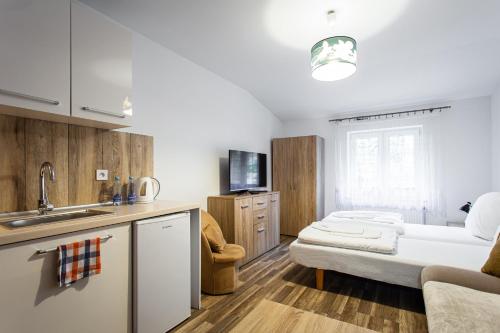 a kitchen with a sink and a living room at Pokoje Gold Centrum in Koszalin