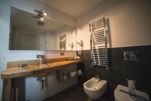 a bathroom with a sink and a toilet and a mirror at Serendipity Hotel in Sauze dʼOulx