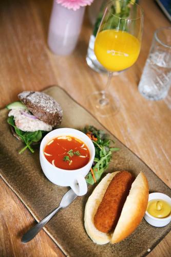 a plate of soup and a sandwich and a glass of orange juice at Van der Valk Hotel Akersloot / A9 ALKMAAR in Akersloot