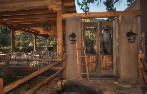 a wooden porch with a ladder and a table at Abiquiu Inn in Abiquiu
