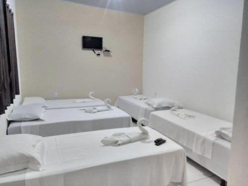 a room with three beds and a tv on the wall at Pousada Bela Vista de Mateiros in Mateiros