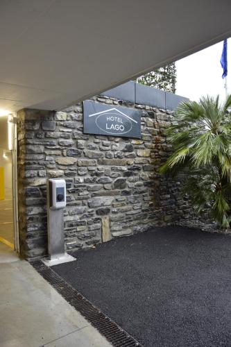 a sign on a building with a stone wall at Hotel Lago in Torno