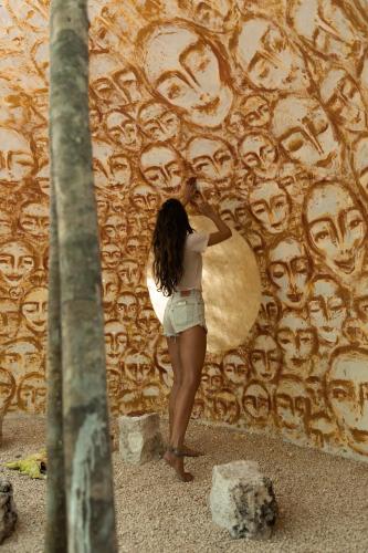 a woman standing in front of a wall with a surfboard at Hotel Holistika Tulum in Tulum