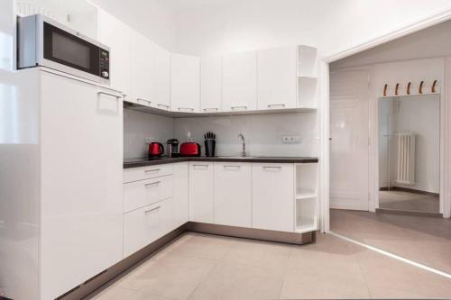 - une cuisine blanche avec des placards blancs et un évier dans l'établissement Contemporary City Apartment Váci Utca, à Budapest