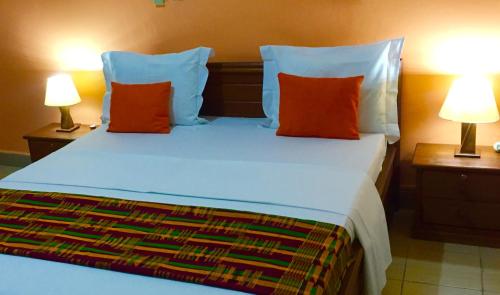 a bedroom with a bed with orange pillows and two lamps at Bolo Residence Douala in Douala