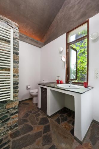 a bathroom with a sink and a toilet and a window at Studios Kyparissi & Spa in Tiros