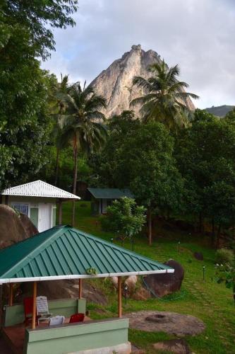 a house with a green roof with a mountain in the background at Diga vista resorts in Palakkad
