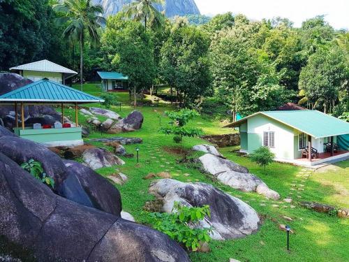 a garden with rocks and a small house in the background at Diga vista resorts in Palakkad