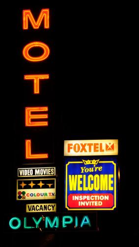 a sign for a hotel with neon signs on it at Olympia Motel in Queanbeyan