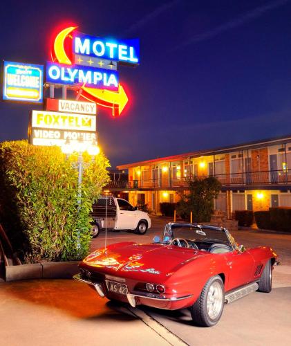 a red car parked in front of a motel at Olympia Motel in Queanbeyan