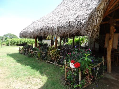 a hut with a bunch of flowers in front of it at Badaboom Hostal & Surf in Aposentillo